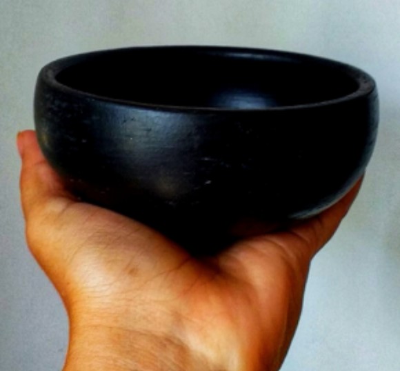 Cuenco de cerámica negra sostenido en la mano
